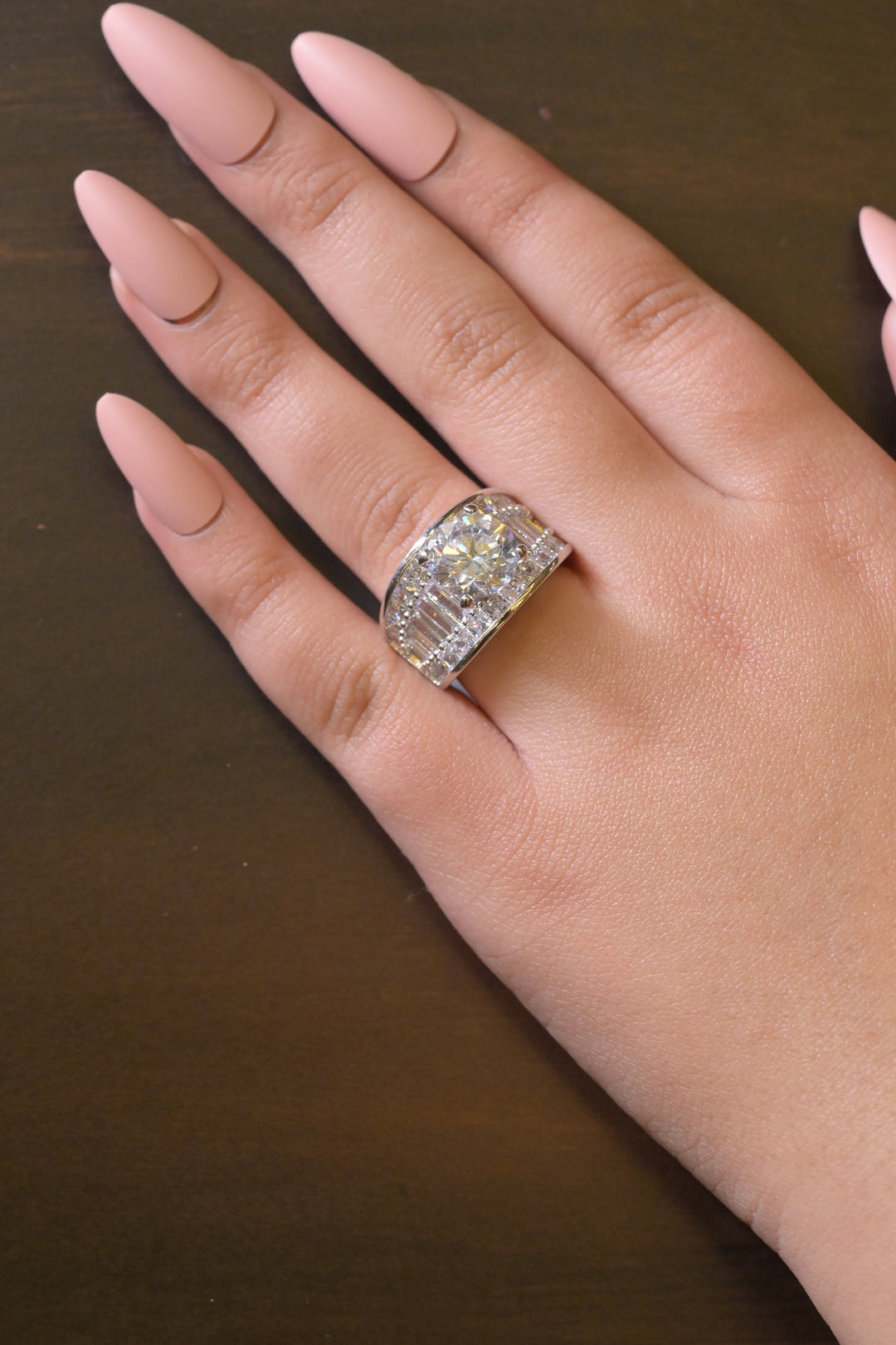 Hand wearing a diamond ring on a dark background